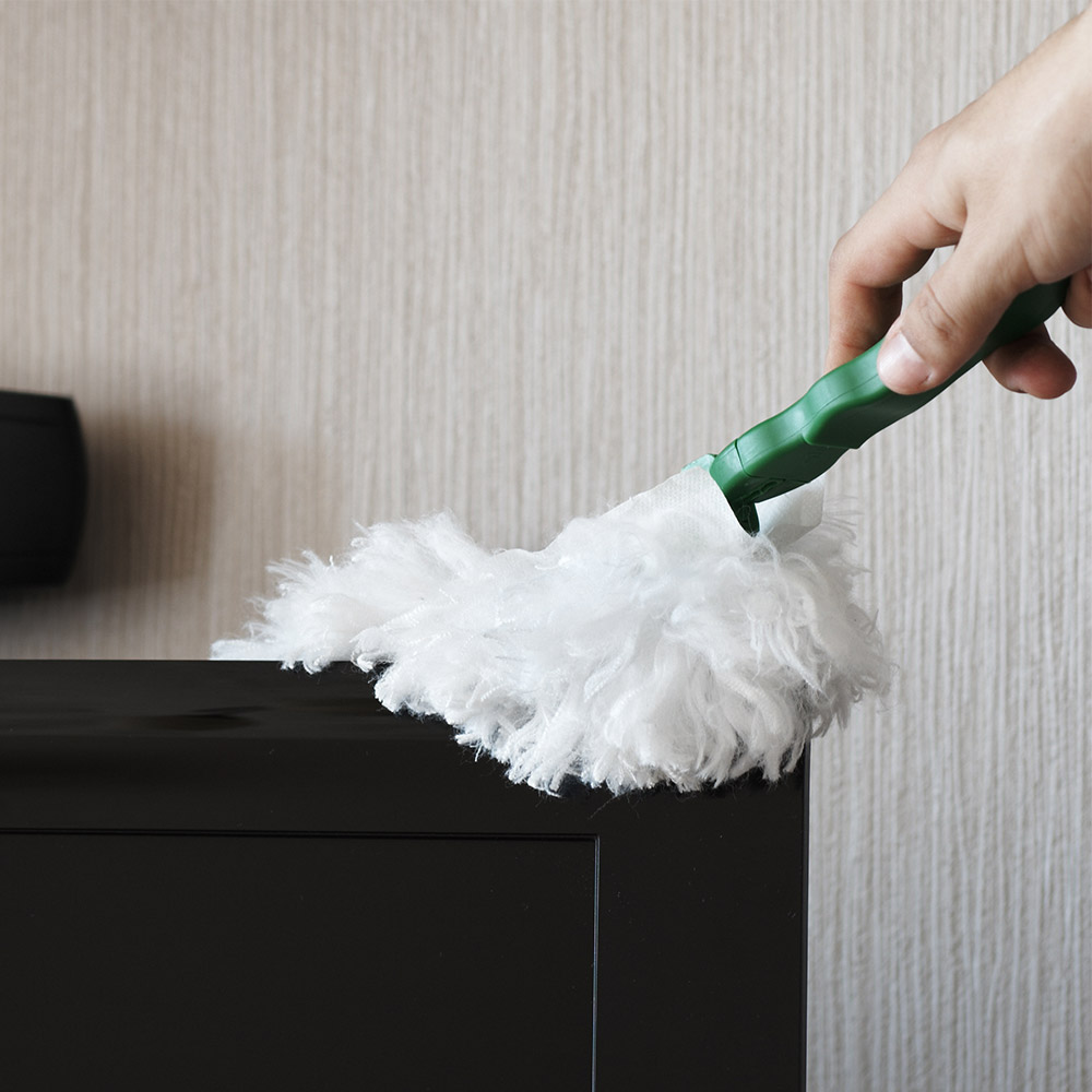 photo of a person dusting off a dresser